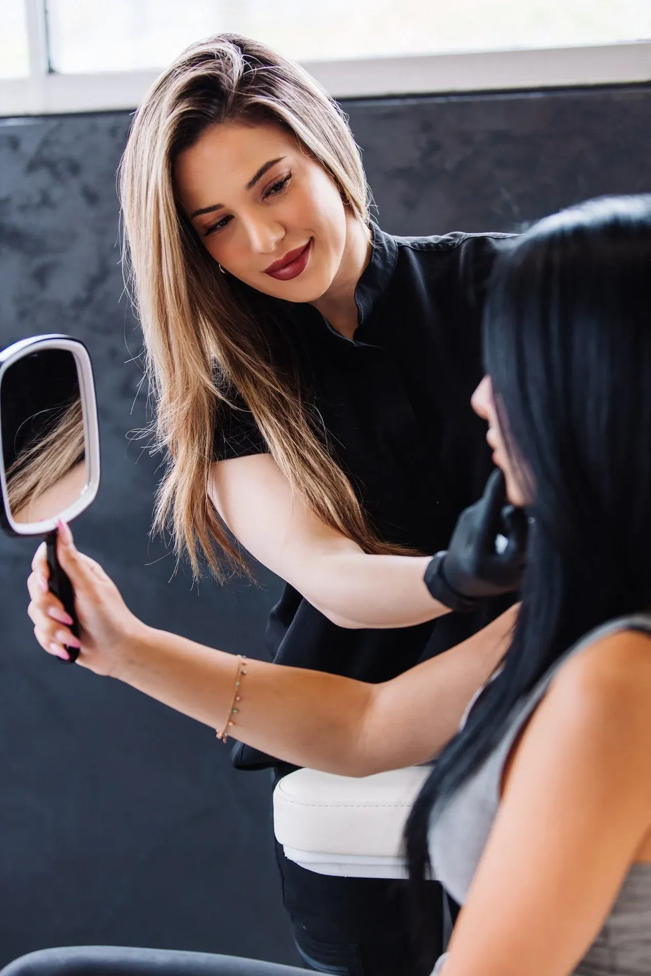 Katherine showing a patient her skin in a hand mirror